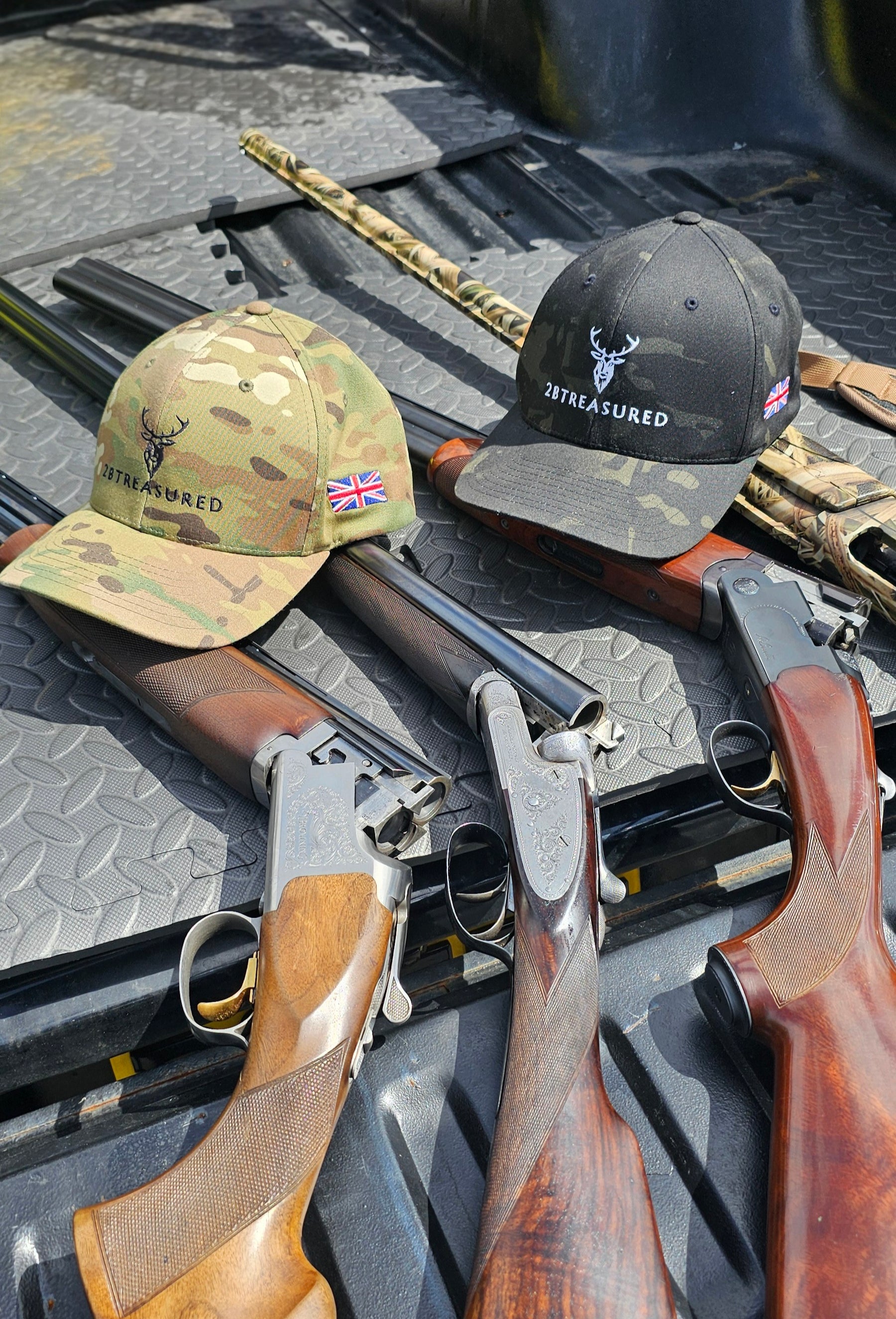 Camo hats resting on a truck tailgate on top of shotguns