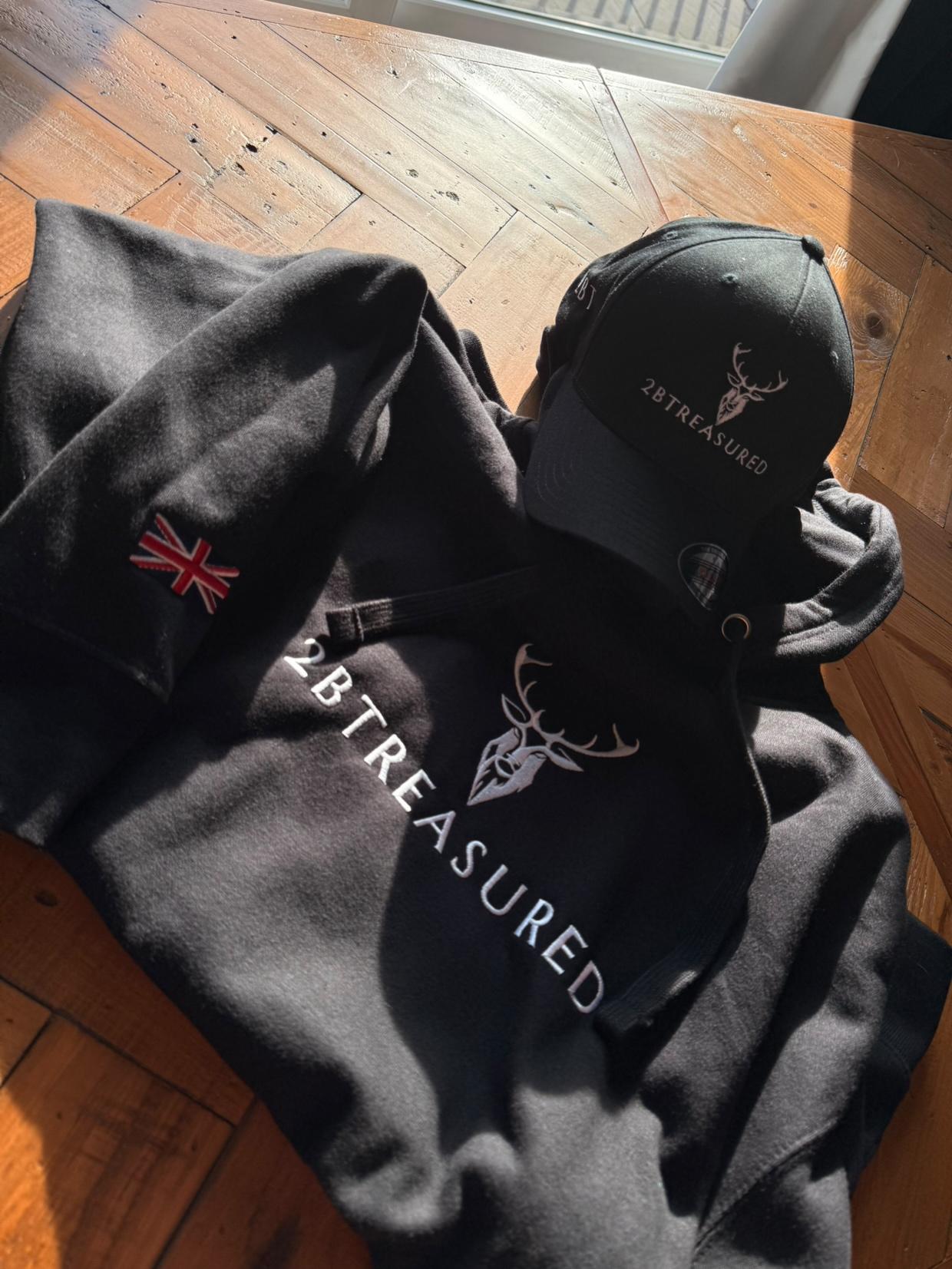 Embroidered Lomond Hoodie with British Flag and 2BTreasured cap resting on a table