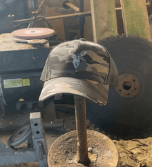Embroidered Stag Camouflage Trucker Hat olive camo featured on a stick in a barn