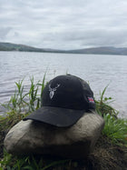 Embroidered Stag Structured Camo Cap, Multicam with British Flag on a rock next to water