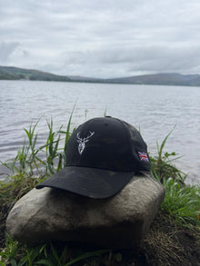 Embroidered Stag Structured Camo Cap, Multicam with British Flag on a rock next to water
