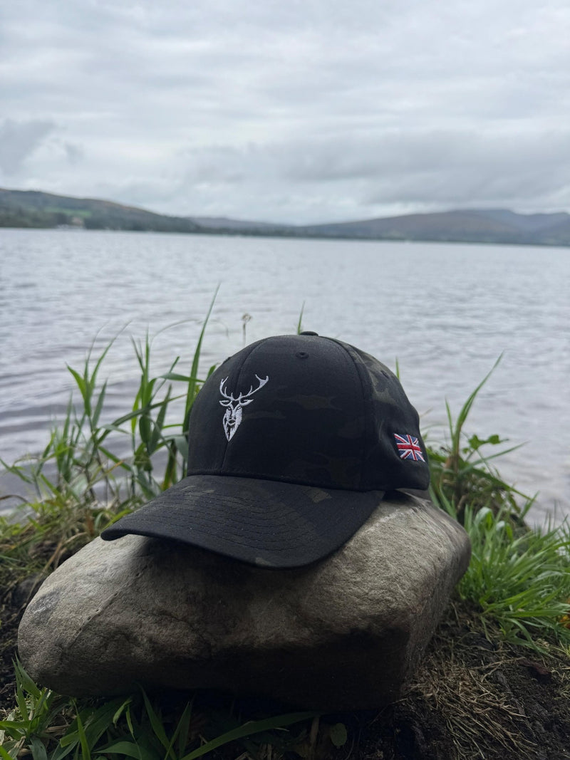 Embroidered Stag Structured Camo Cap, Multicam with British Flag on a rock next to water