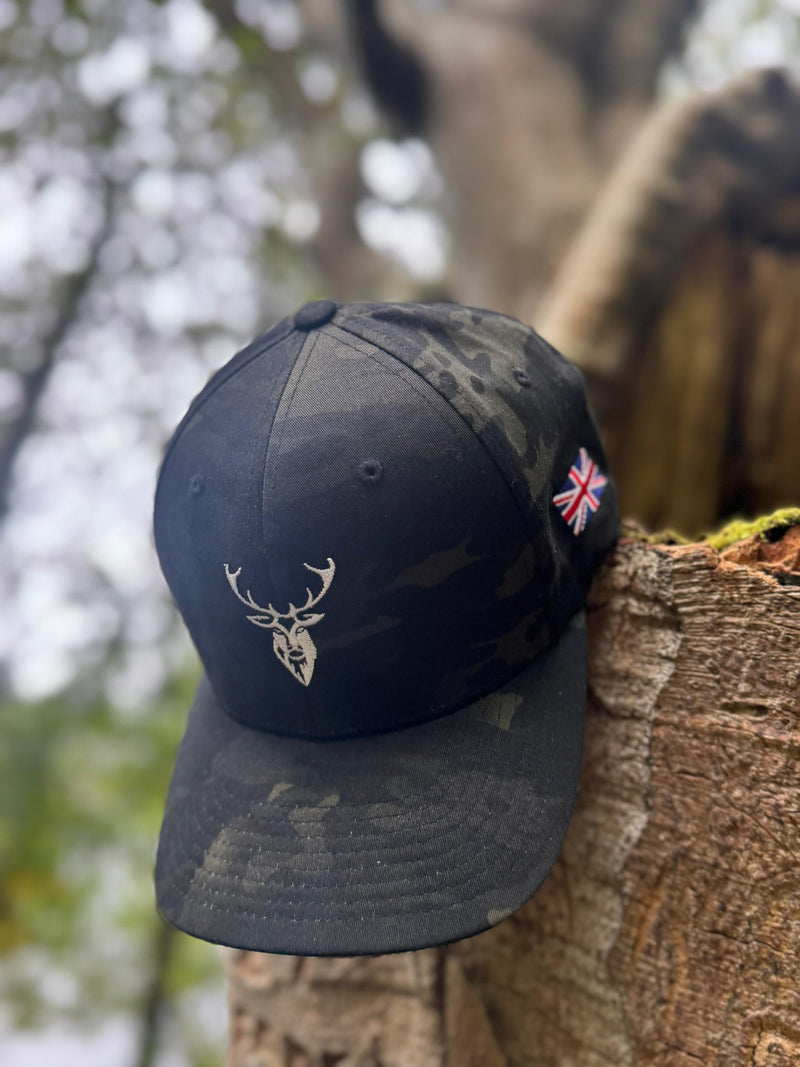 Embroidered Stag Structured Camo Cap, Multicam with British Flag handing from wooden log