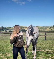 Woman model wearing Embroidered Stagmoor Quarter Zip Country Green with a horse in a field