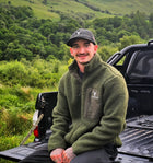 Male model wearing Snowdon Sherpa Fleece Army Green colour from brand 2BTreasured on the back of a truck in the countryside 