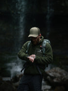 Model in the Snowdon Sherpa Fleece Army Green colour next to a waterfall 